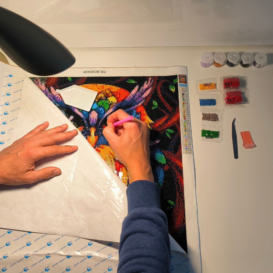 Diamond painting workspace setup with lamp, trays and canvas
