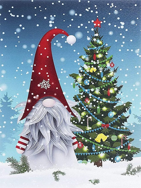 A festive winter illustration featuring a snowman gnome with a tall red hat and white beard standing beside a decorated Christmas tree in the snow, with falling snowflakes in the background. Christmas Gnome with the Tree - Diamond Painting