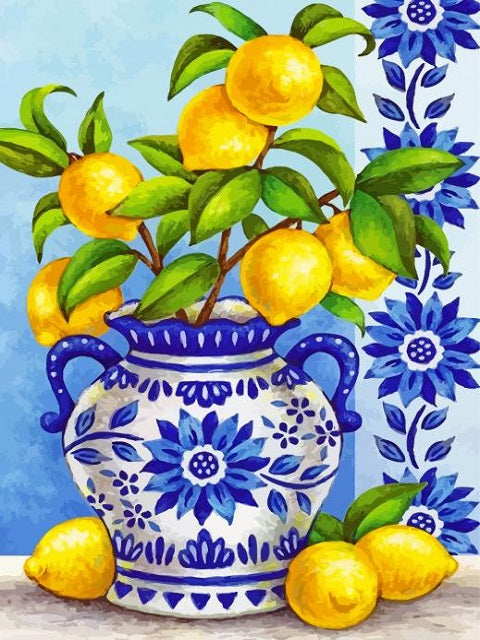 A colorful still life painting of lemons on a branch with green leaves, arranged in a blue and white patterned ceramic vase, with additional lemons on the surface against a light blue background with blue floral motifs. Lemons - Diamond Painting